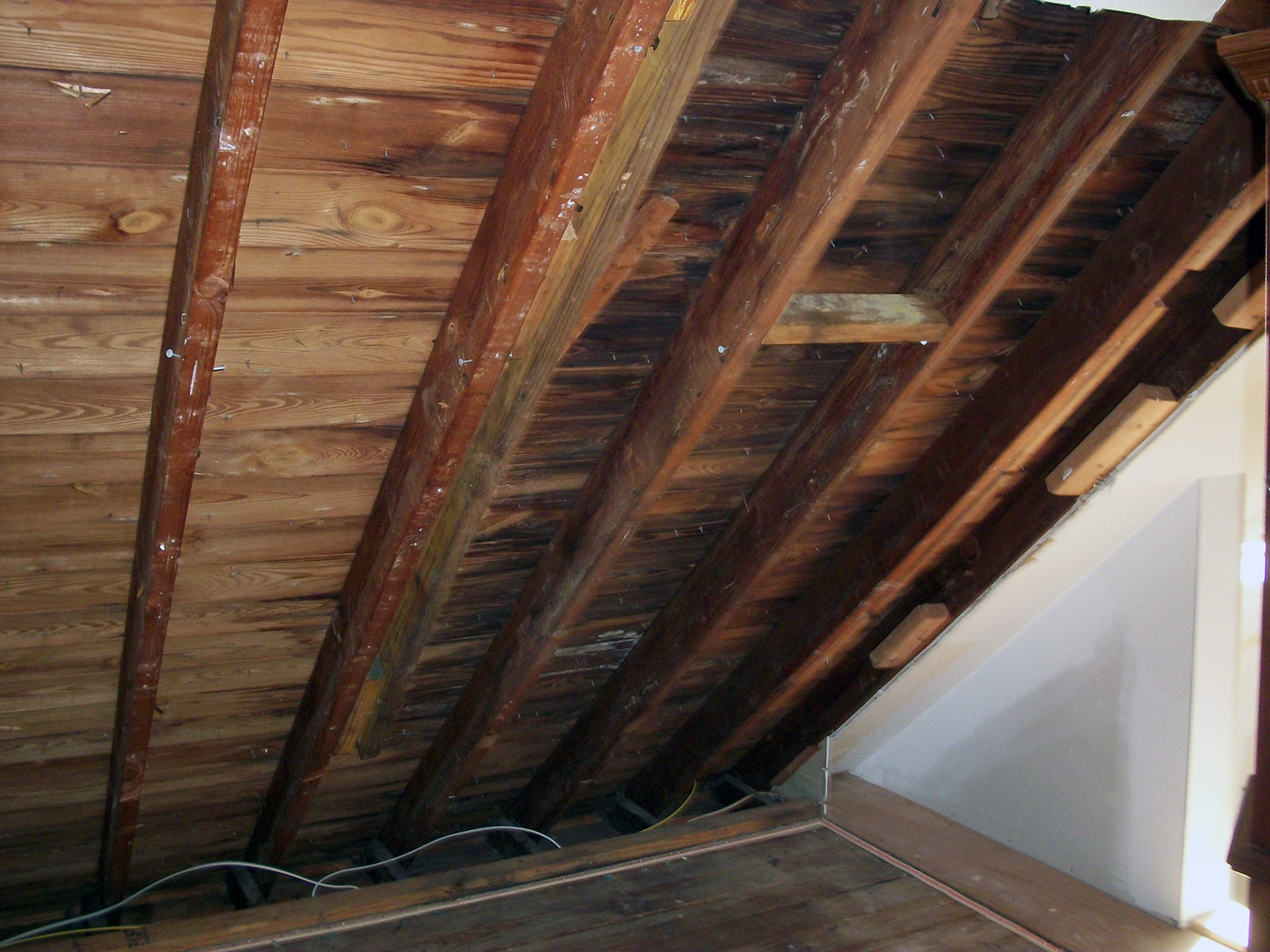 Wet roof boards inside the attic with mold spreading on contaminated surface