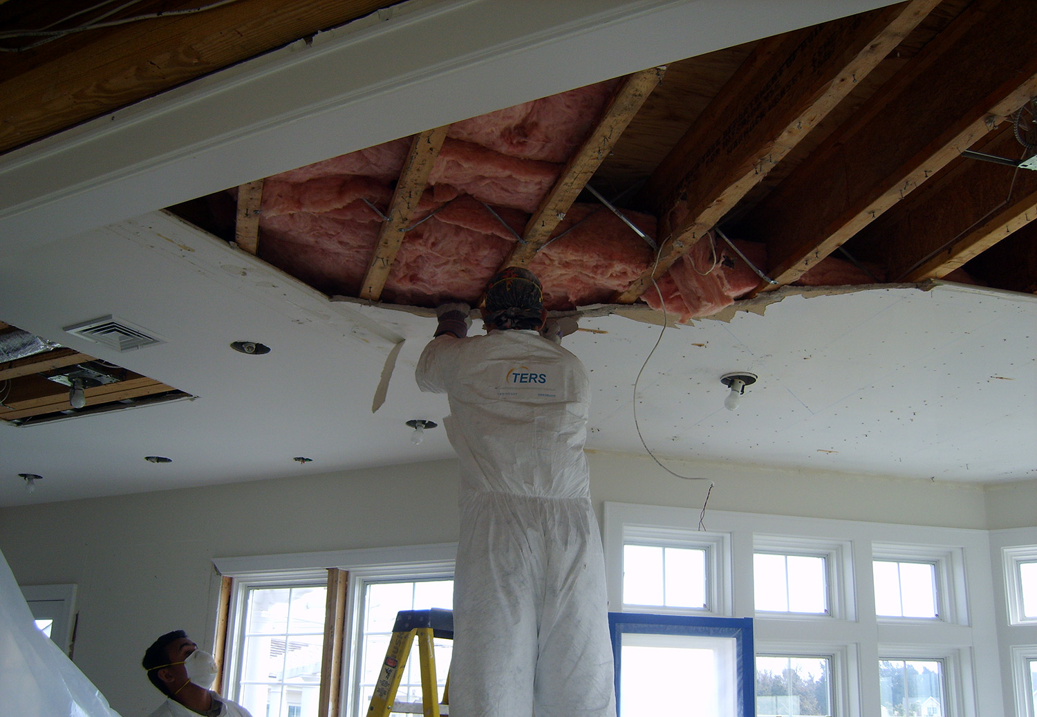 TERS restoration worker removing ceiling drywall to assess the water and mold damage